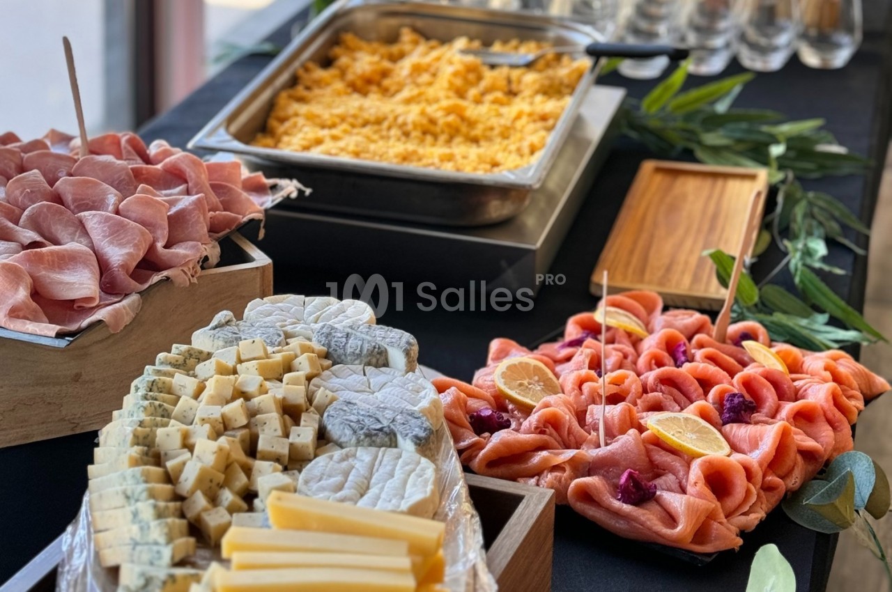 Plateau de charcuterie, fromages variés et saumon fumé avec citron, disposés sur une table de buffet.