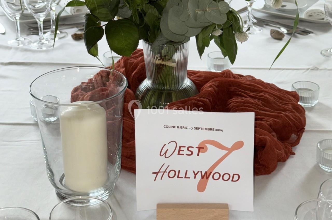 Centre de table avec une bougie dans un verre, un vase de fleurs et une carte indiquant ’West Hollywood’.