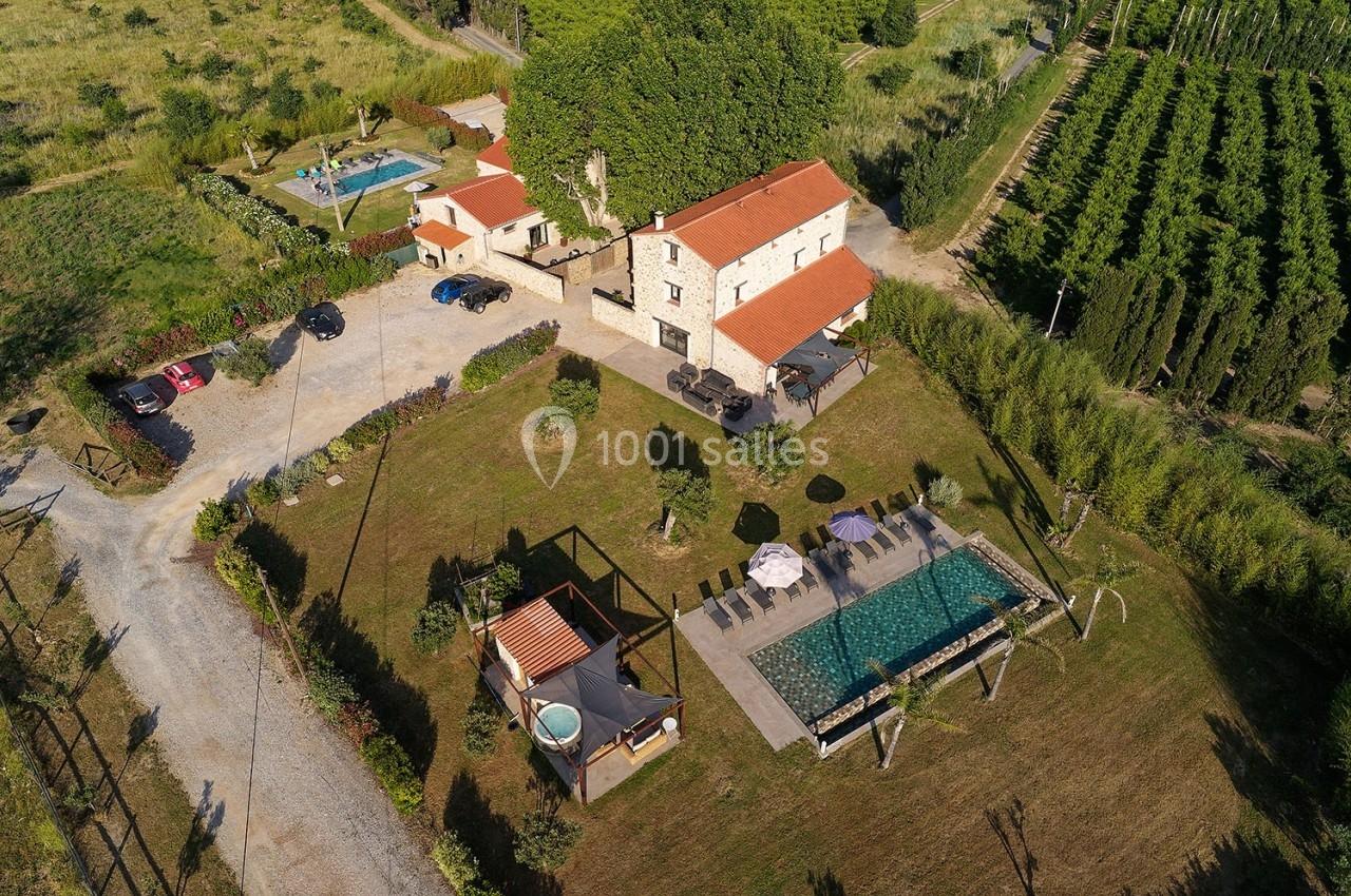 Vue aérienne d'une maison en pierre avec piscine, jardin, terrasse et espaces verts environnants.