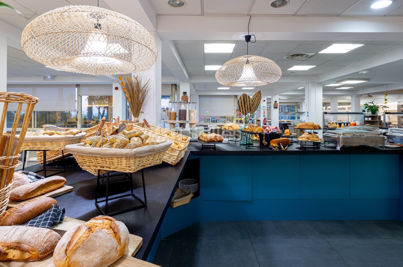 Buffet de pains variés disposés dans des paniers en osier sur un comptoir dans un espace lumineux.
