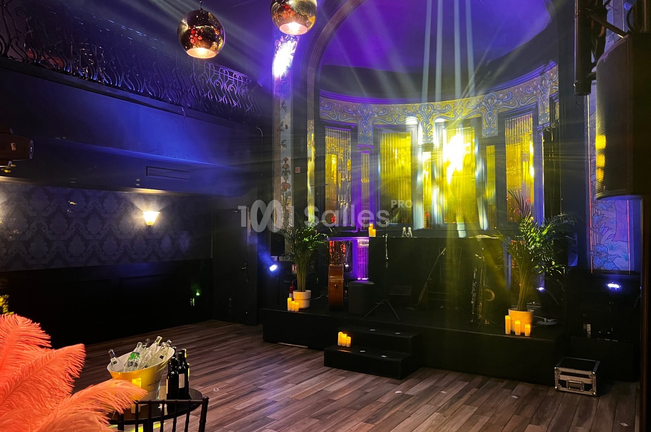 Salle de réception avec piste de danse, éclairages colorés, décorations élégantes et ambiance tamisée.