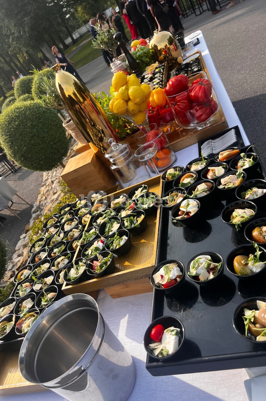 Buffet en extérieur avec verrines, salades et légumes colorés disposés sur une table blanche.