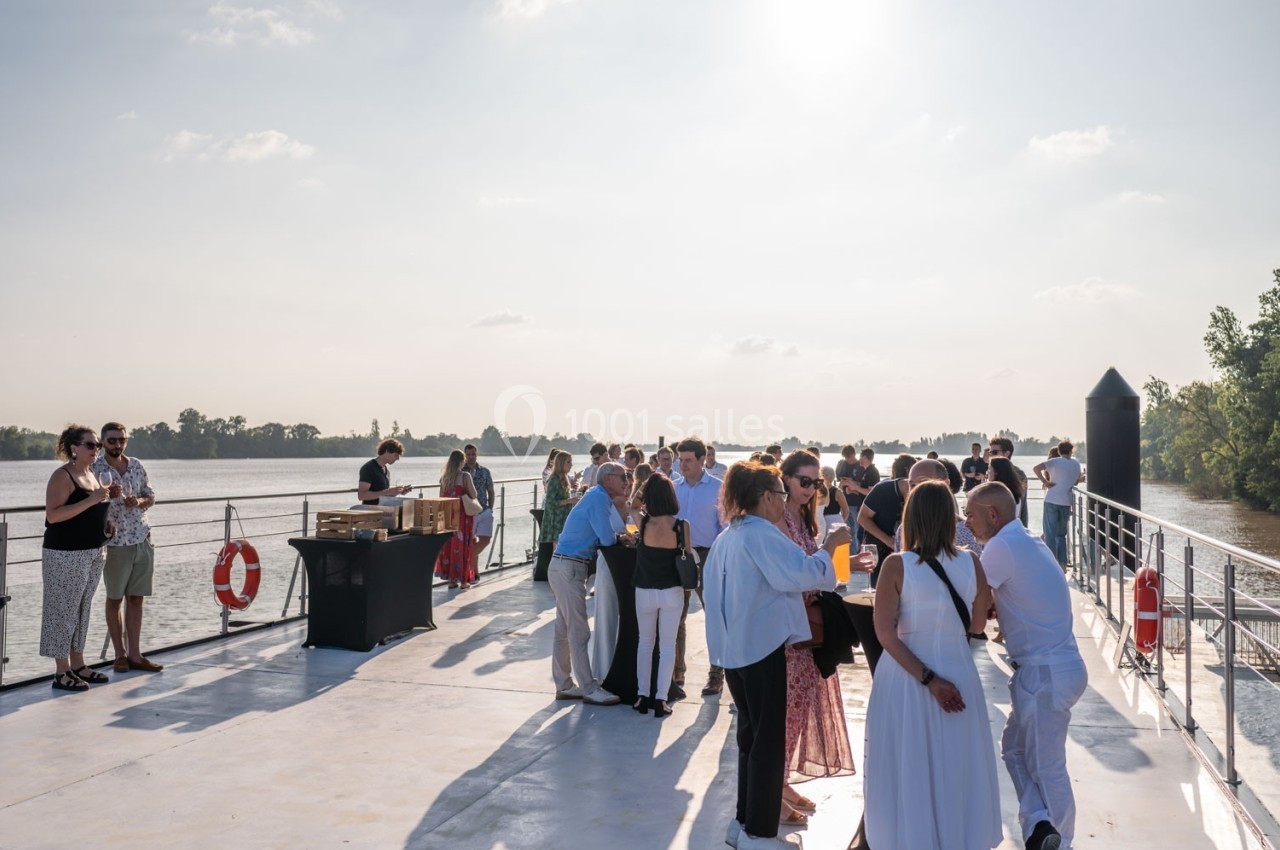 Des personnes discutent et partagent un moment convivial sur le pont d'un bateau naviguant sur une rivière par temps…