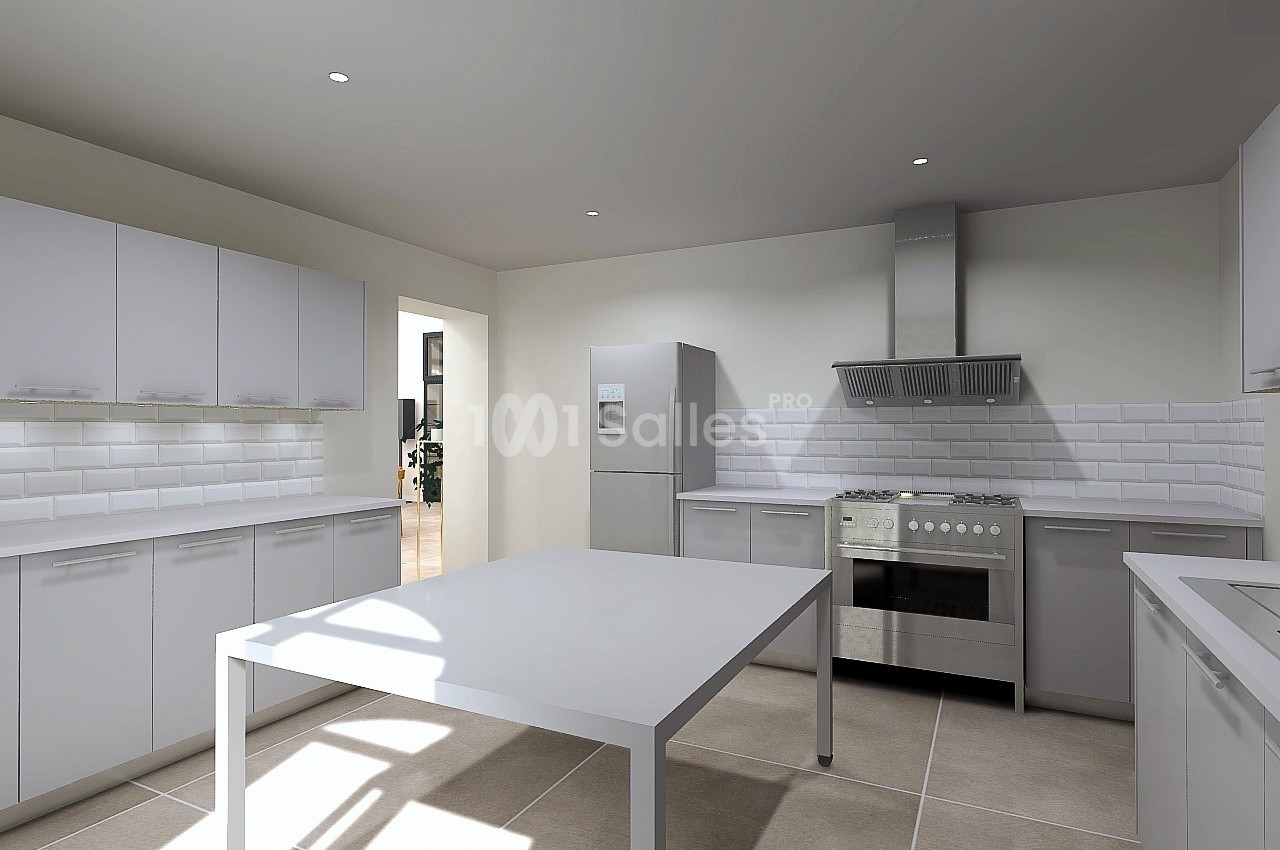 Cuisine moderne avec meubles blancs, table centrale, électroménagers en acier inoxydable et carrelage beige.
