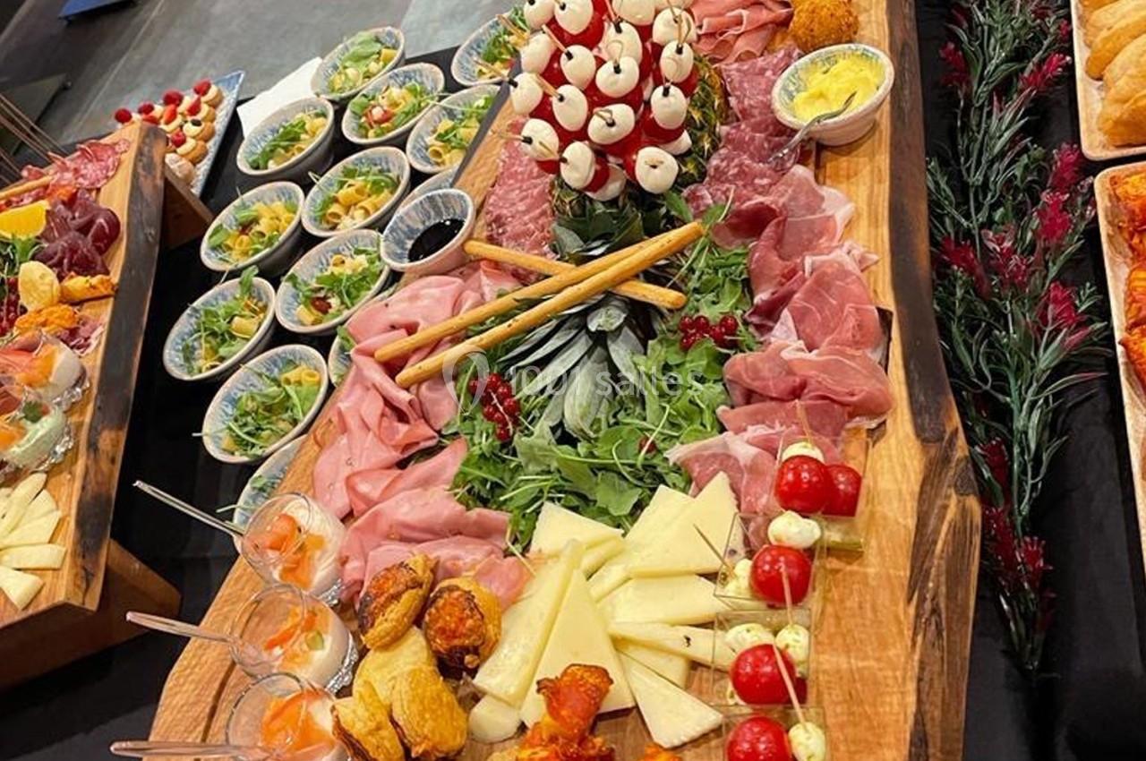 Plateau de charcuteries, fromages, crudités et verrines, disposé sur une table en bois pour un buffet.