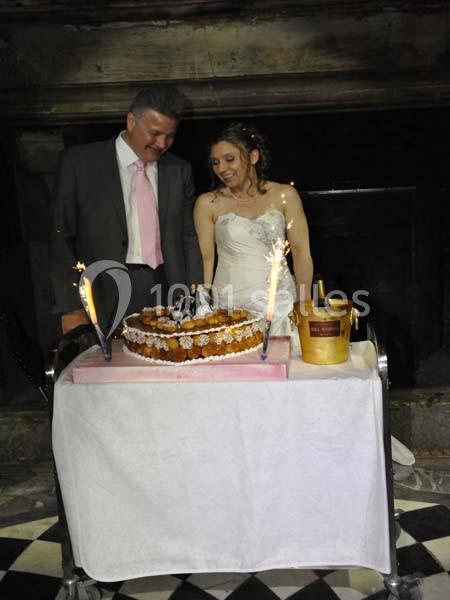 Un couple en tenue de mariage se tient devant une pièce montée décorée de figurines, avec des étincelles allumées.