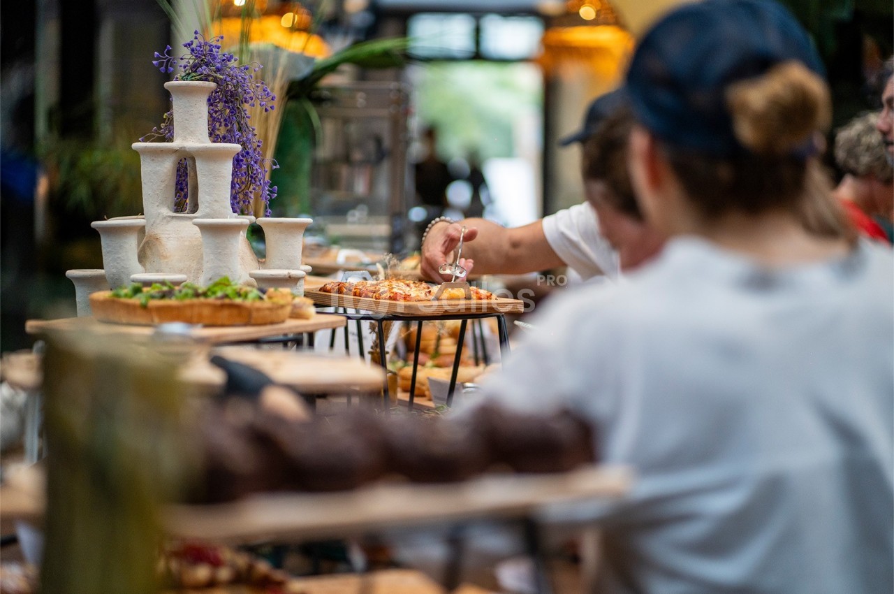 Personnes se servant à un buffet garni de plats variés, avec des fleurs décoratives en arrière-plan.