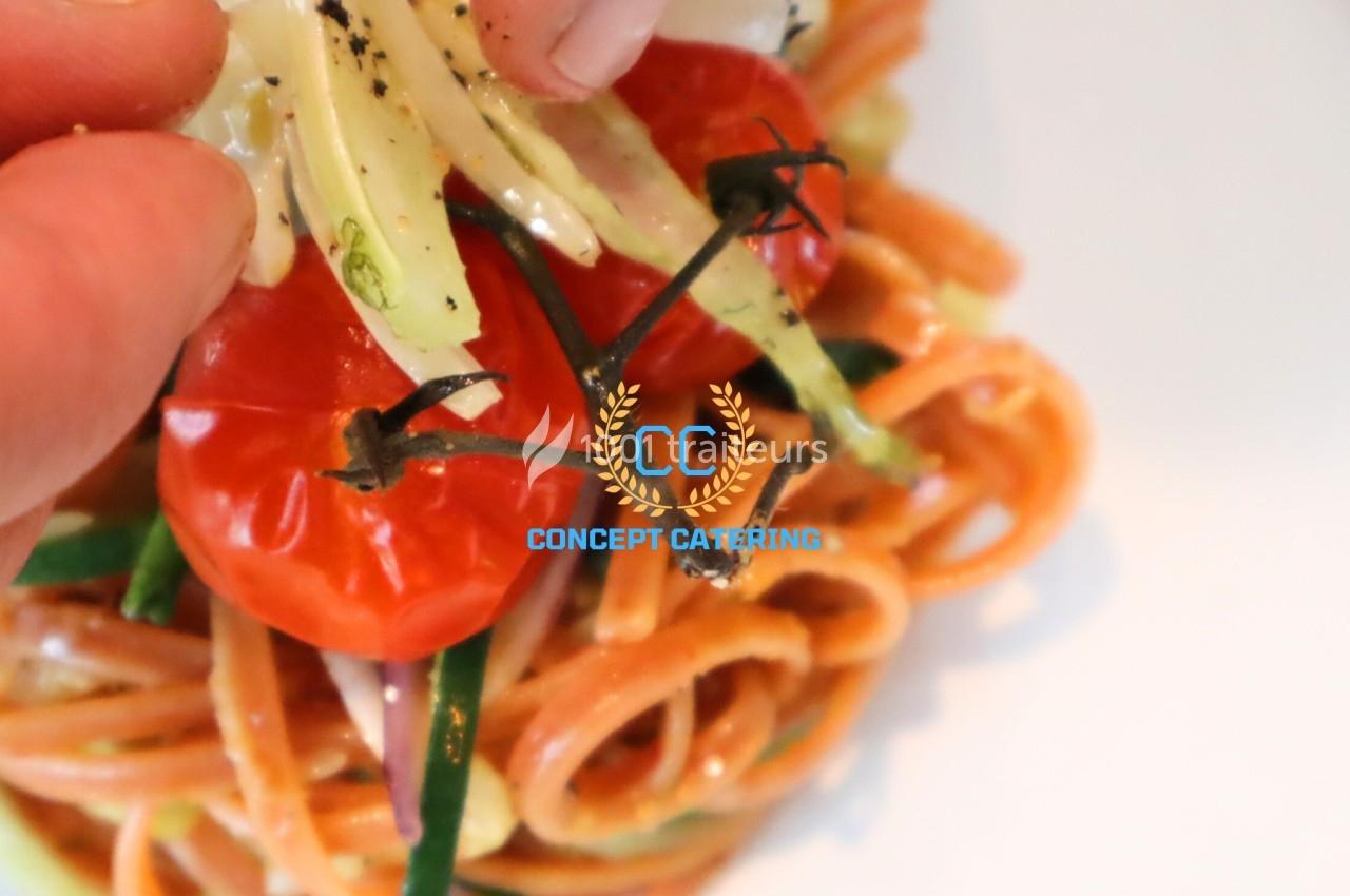 Plat de pâtes colorées avec tomates cerises rôties, courgettes et sauce crémeuse, décoré avec soin.