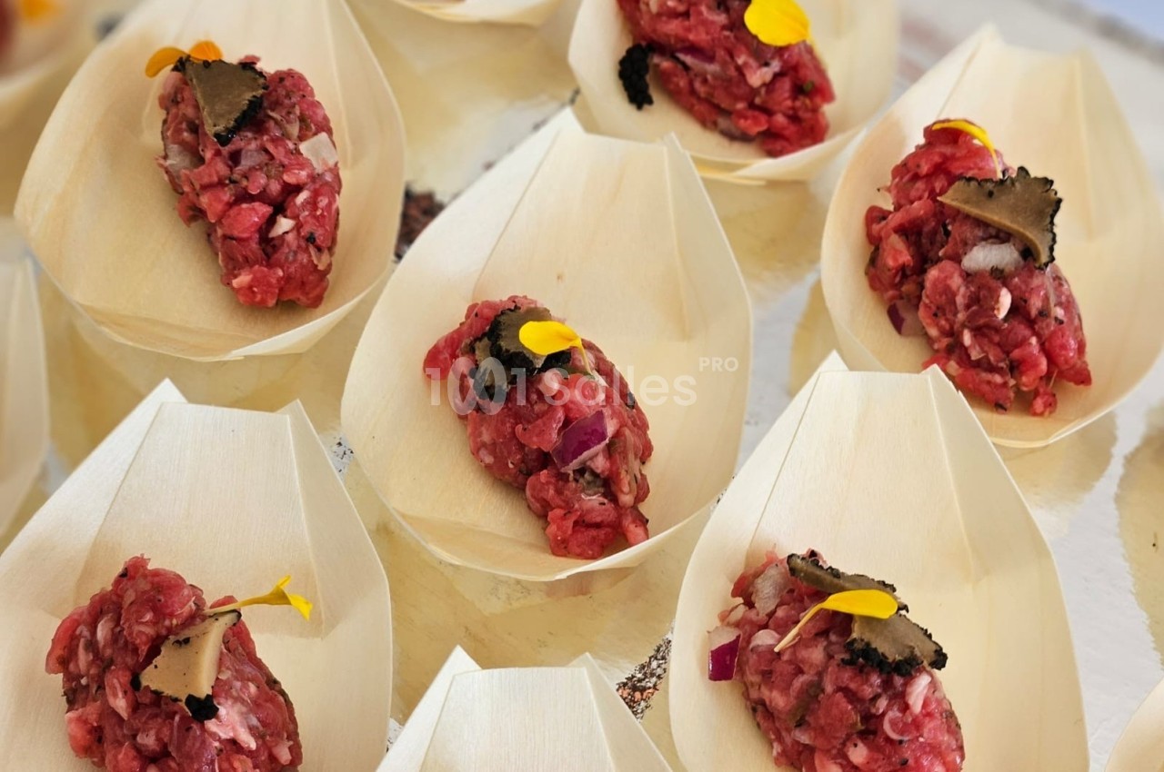 Portions de tartare de bœuf garnies de truffes et de fleurs comestibles, présentées dans des coupelles en bois.