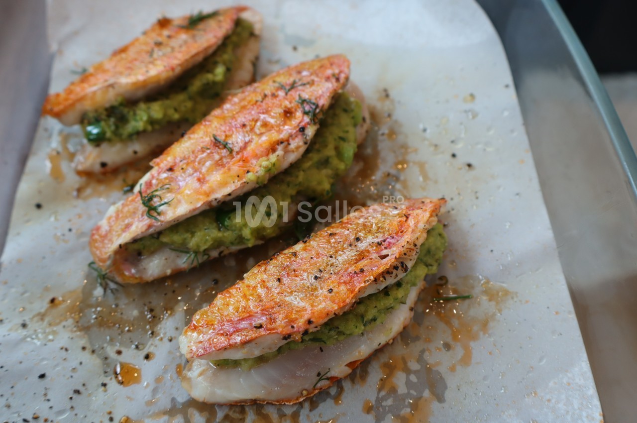 Filets de poisson garnis d'une farce verte, cuits au four sur une plaque recouverte de papier cuisson.