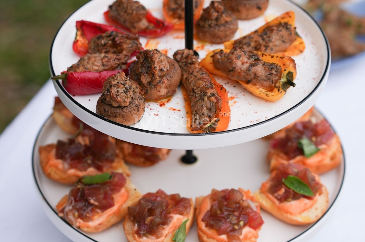 Plateau à deux niveaux avec champignons farcis, poivrons grillés et toasts garnis de tomates et herbes fraîches.