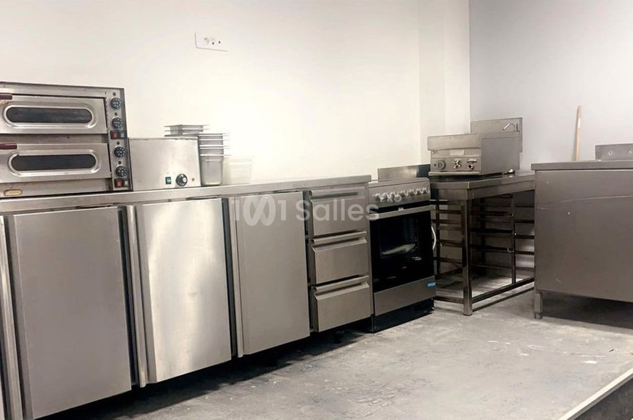 Cuisine professionnelle avec équipements en inox, comprenant fours, plaques de cuisson, plans de travail et rangements.