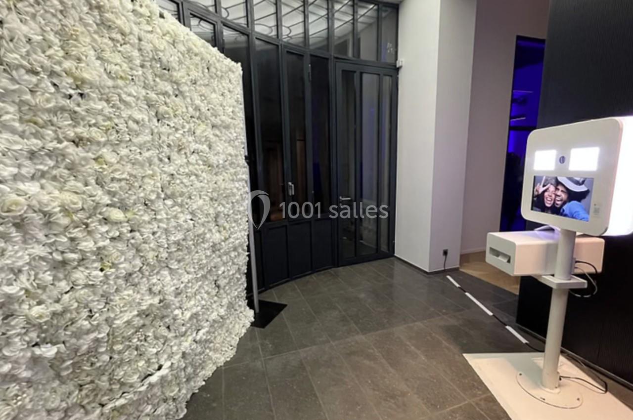 Mur de fleurs blanches et borne photo lumineuse installés dans un espace intérieur moderne.
