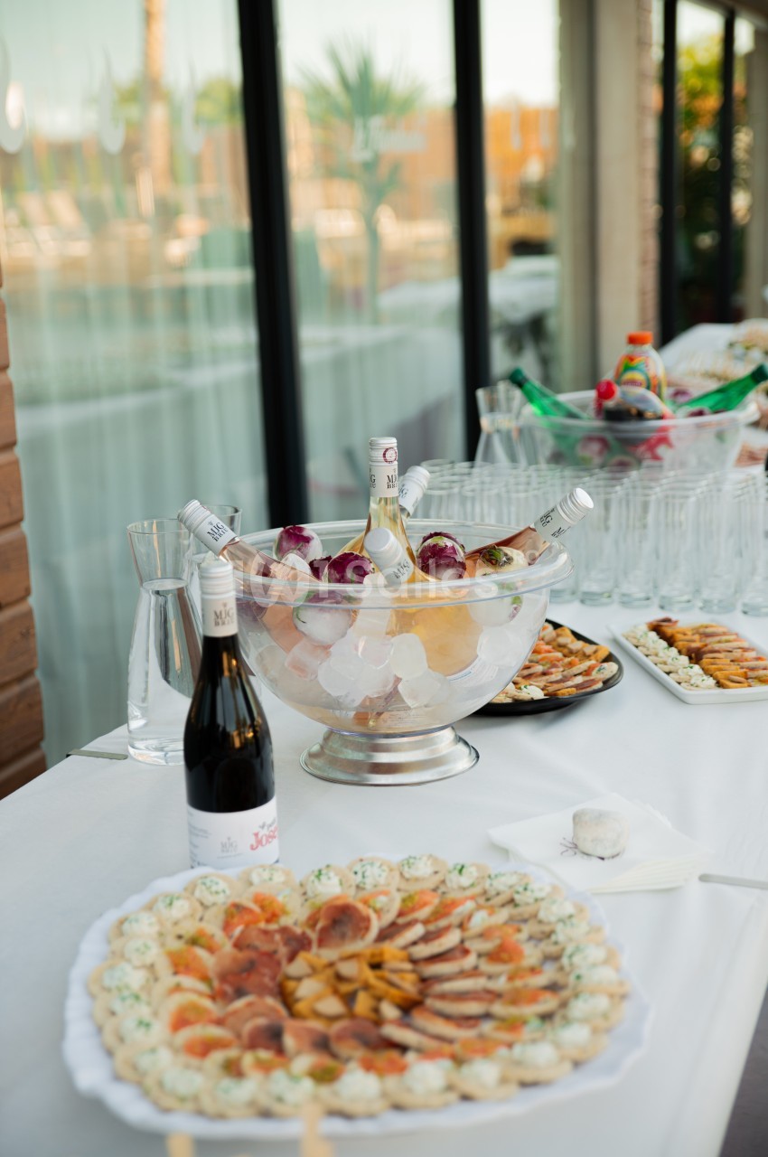 Table dressée avec des amuse-bouches, une coupe de champagne sur glace et des verres alignés en arrière-plan.