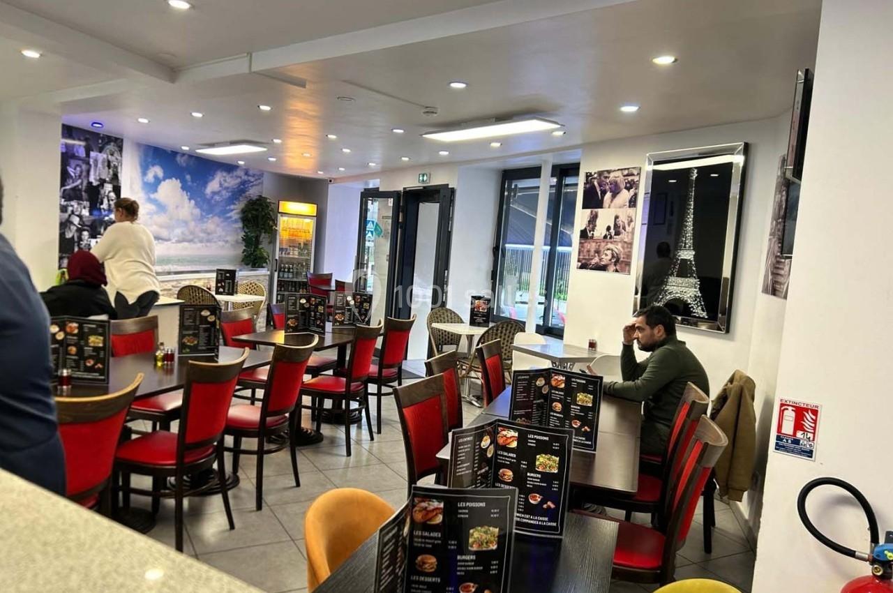 Salle de restaurant lumineuse avec des tables dressées, des menus visibles et une décoration murale sur Paris.