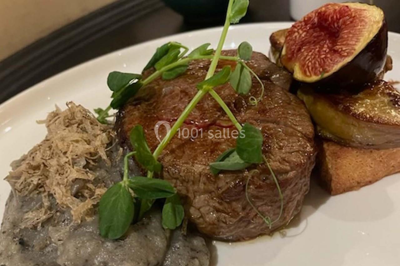 Assiette avec un filet de viande, purée garnie de truffes, foie gras sur pain grillé et figue fraîche.