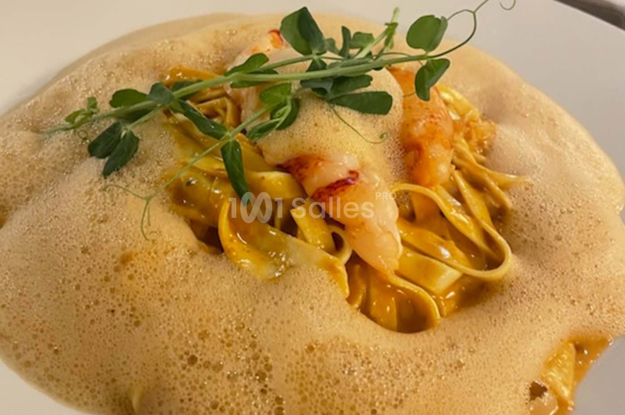 Assiette de pâtes fraîches aux crevettes, nappées d'une émulsion légère et garnies de pousses vertes.
