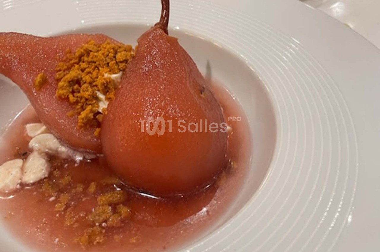 Poires pochées au sirop rouge servies avec une garniture croustillante et une sauce légère dans une assiette blanche.