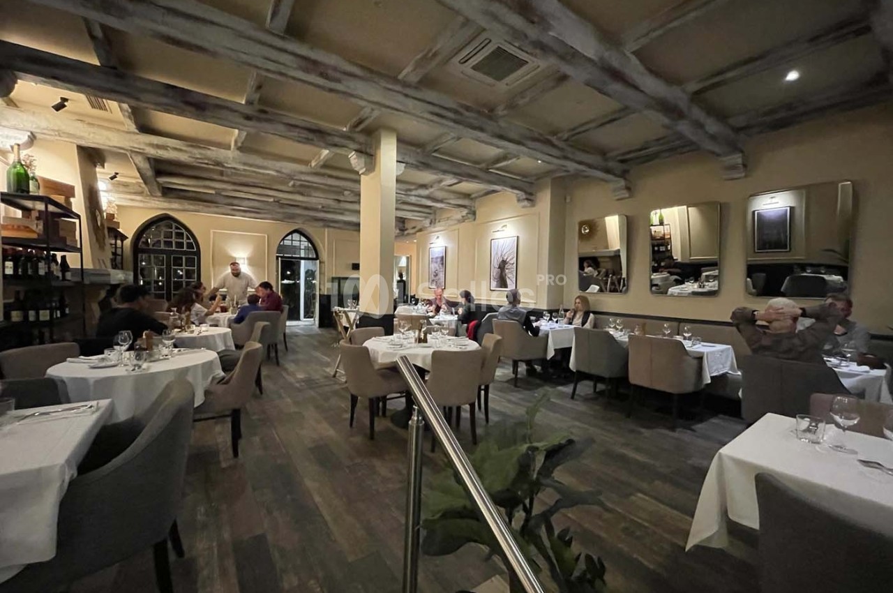 Salle de restaurant élégante avec tables dressées, clients attablés et éclairage tamisé.
