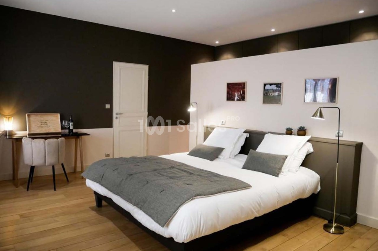 Chambre moderne avec lit double, décoration sobre, bureau en bois et éclairage tamisé sur parquet clair.