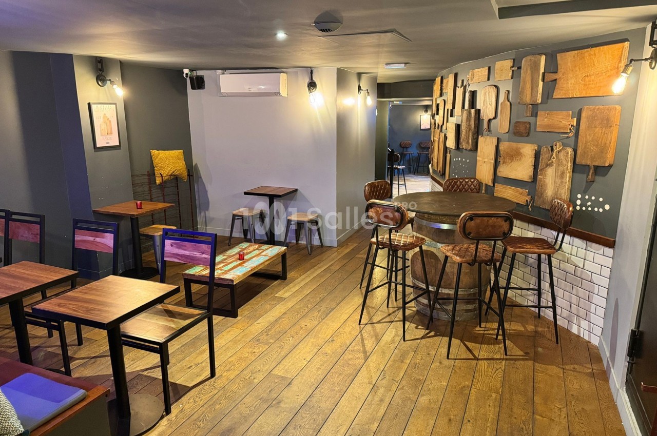 Salle de restaurant avec parquet en bois, tables et chaises modernes, murs décorés de planches en bois.