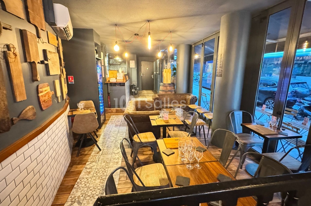 Salle de restaurant chaleureuse avec tables en bois, chaises métalliques, décor mural et éclairage suspendu.