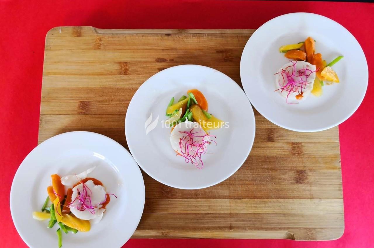 Trois assiettes blanches contenant des légumes colorés et une garniture de pousses roses, disposées sur une planche en bois.