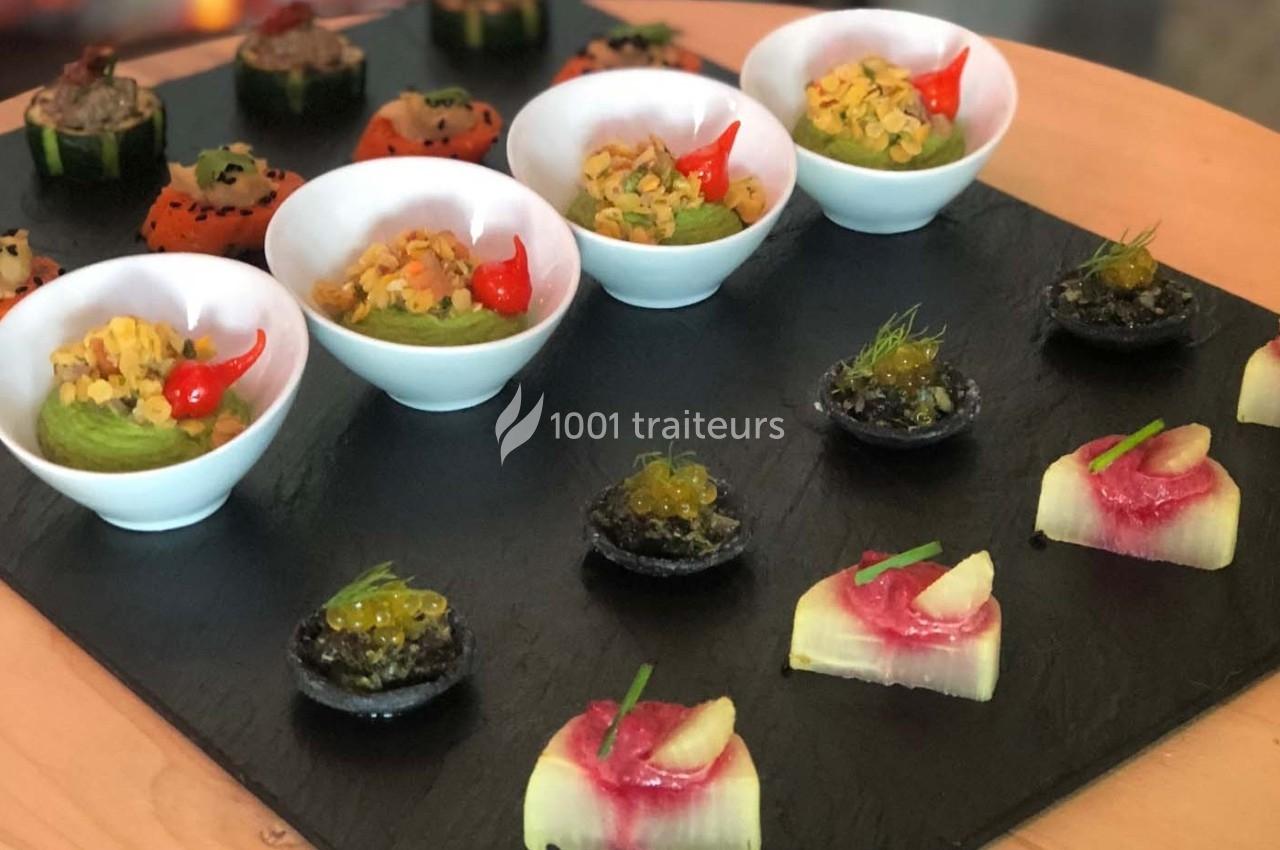 Assortiment de bouchées gastronomiques présentées sur une ardoise, incluant verrines, tartelettes et amuse-bouches colorés.