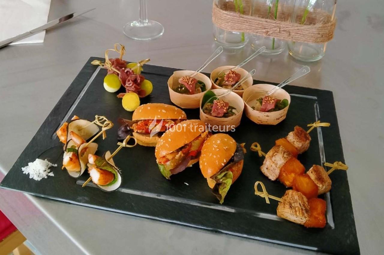 Plateau de bouchées apéritives variées comprenant mini-burgers, brochettes, verrines et cubes de pain doré.