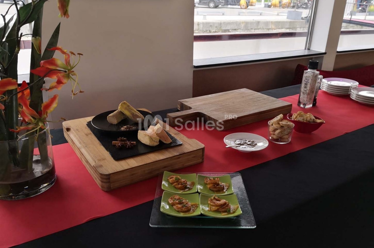 Table avec des planches en bois, des amuse-bouches, des fleurs décoratives et des assiettes sur une nappe rouge et noire.
