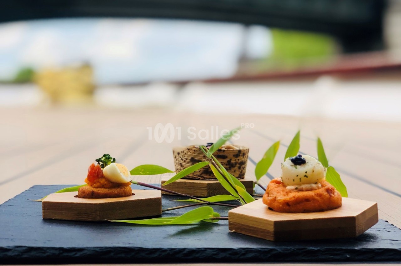 Assortiment de bouchées gastronomiques présentées sur des supports en bois, décorées de feuilles vertes.