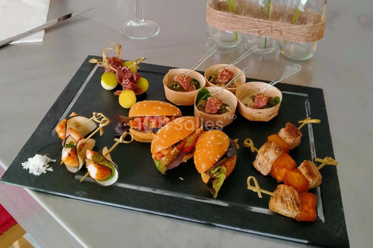 Plateau de bouchées apéritives variées comprenant mini-burgers, brochettes, verrines et cubes de pain doré.