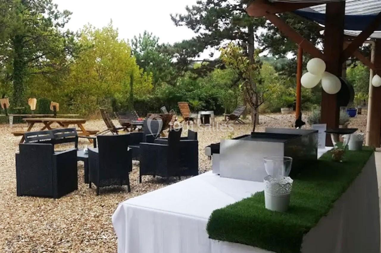Terrasse extérieure avec mobilier de jardin, table dressée et barbecue, entourée de végétation et de ballons décoratifs.