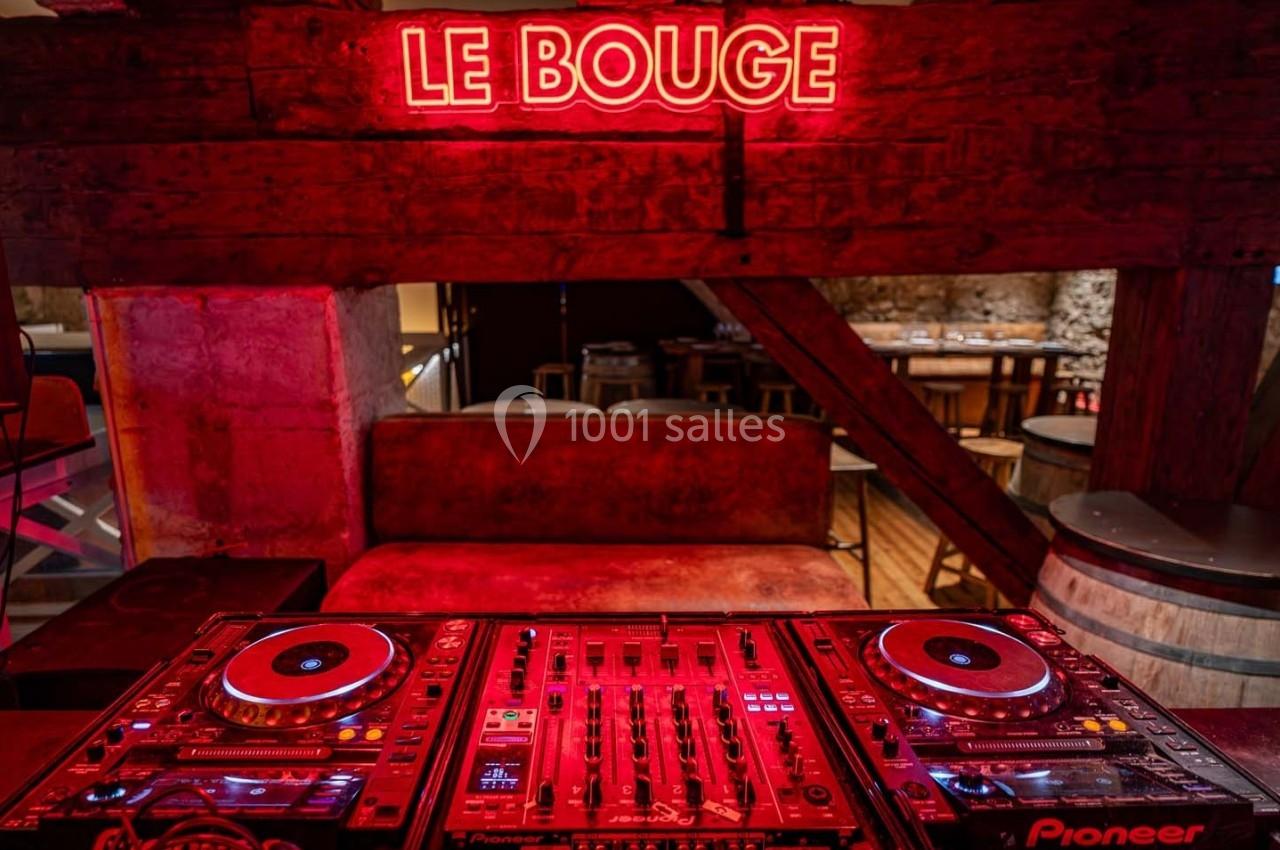 Table de mixage avec platines DJ sous une enseigne lumineuse rouge ’Le Bouge’ dans un décor rustique en bois.