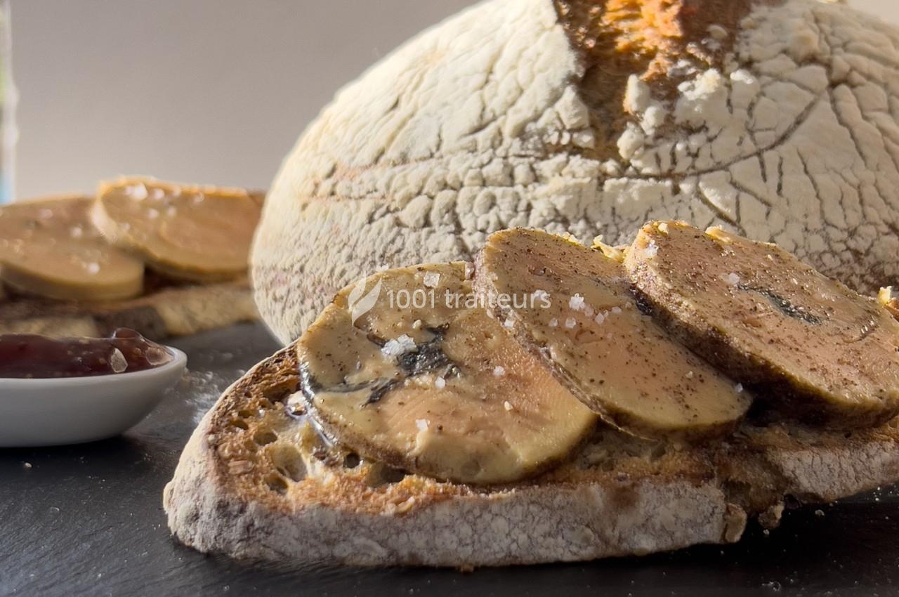 Tranche de pain grillé garnie de foie gras, accompagnée d'une miche de pain et d'une coupelle de confiture.