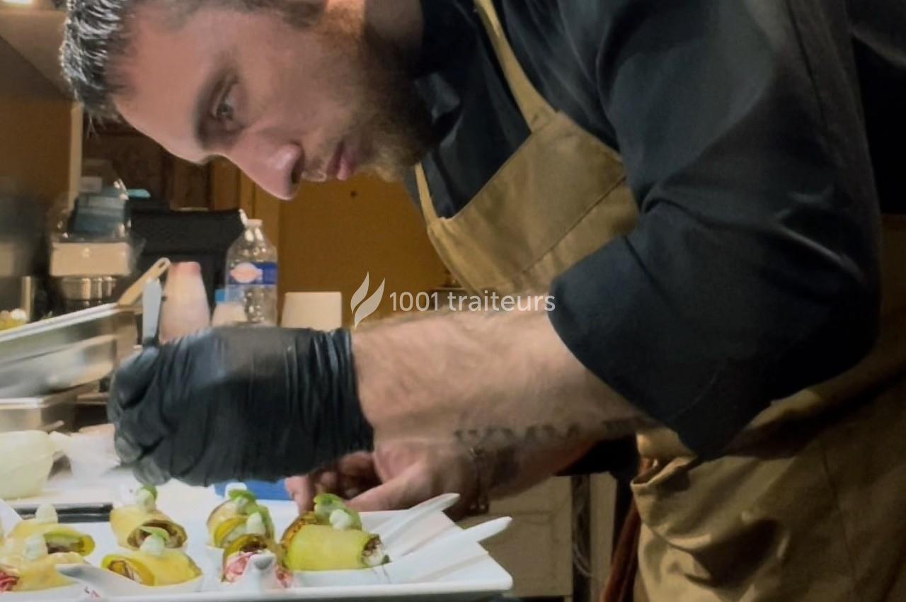 Un chef en tablier prépare soigneusement des plats gastronomiques dans une cuisine professionnelle.