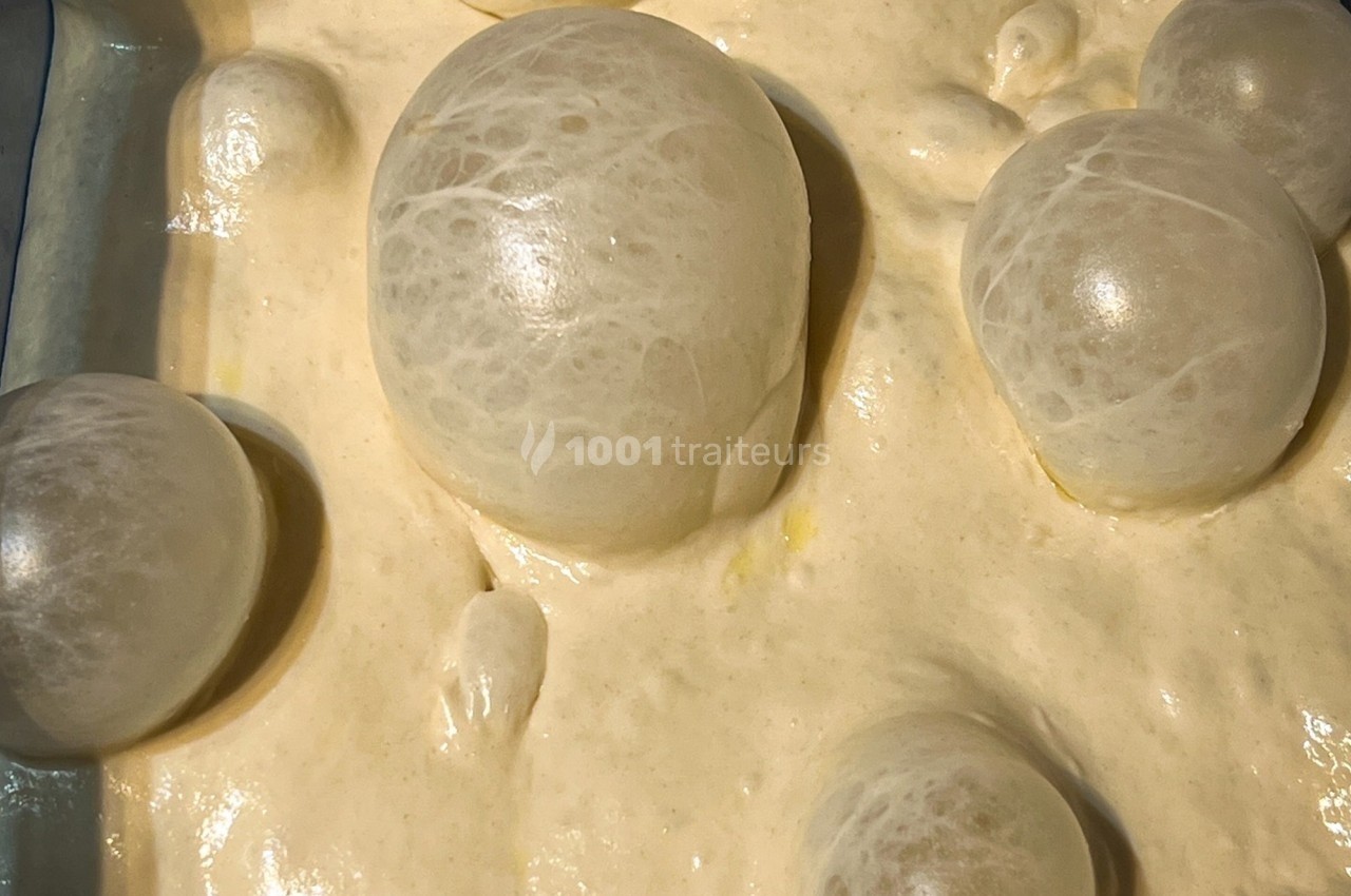 Bulles translucides formées à la surface d'une pâte épaisse de couleur beige dans un récipient.