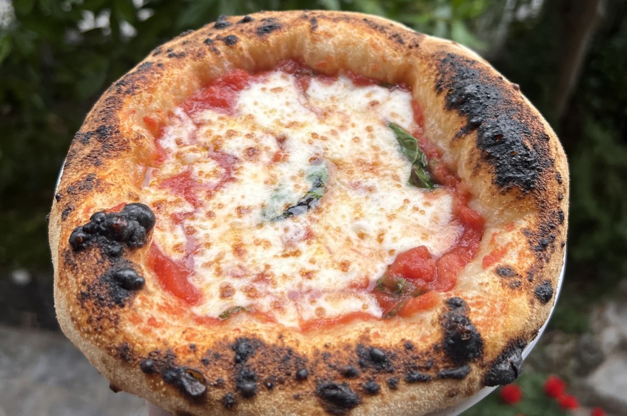 Pizza individuelle avec pâte dorée et garniture de sauce tomate, mozzarella fondue et feuilles de basilic.