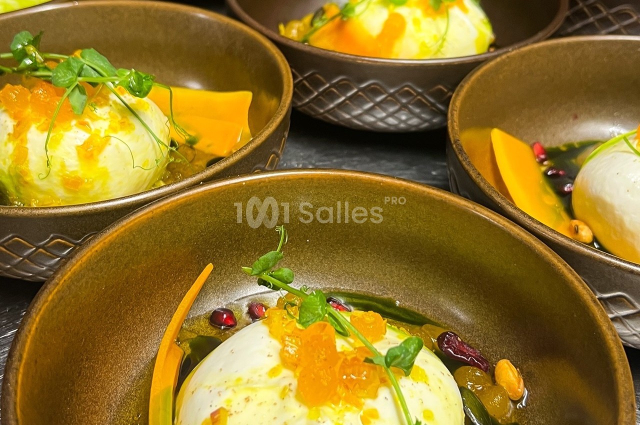 Assiettes en céramique contenant des entrées composées de burrata, légumes, graines et herbes fraîches.