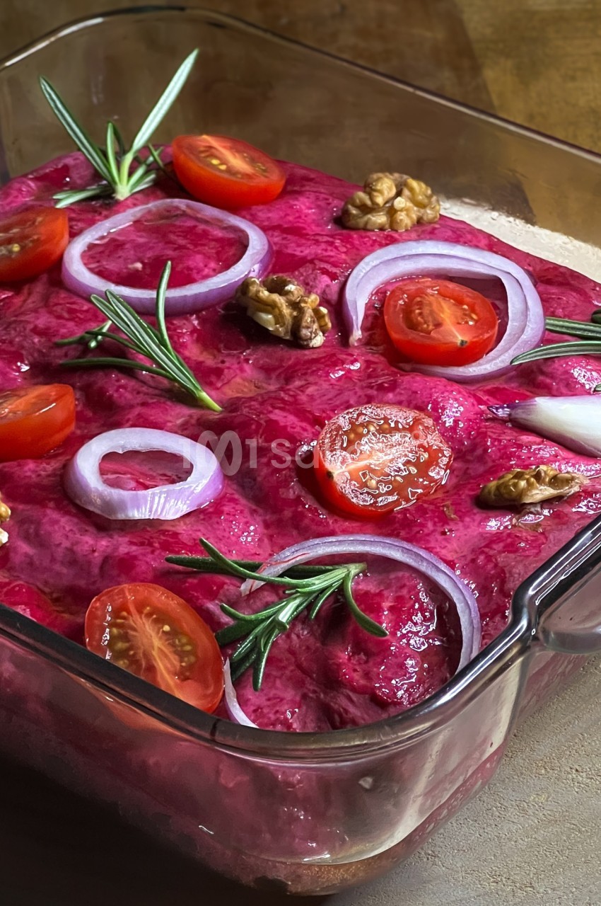 Plat de betterave crémeuse garni de rondelles d'oignon rouge, tomates cerises, noix et brins de romarin.