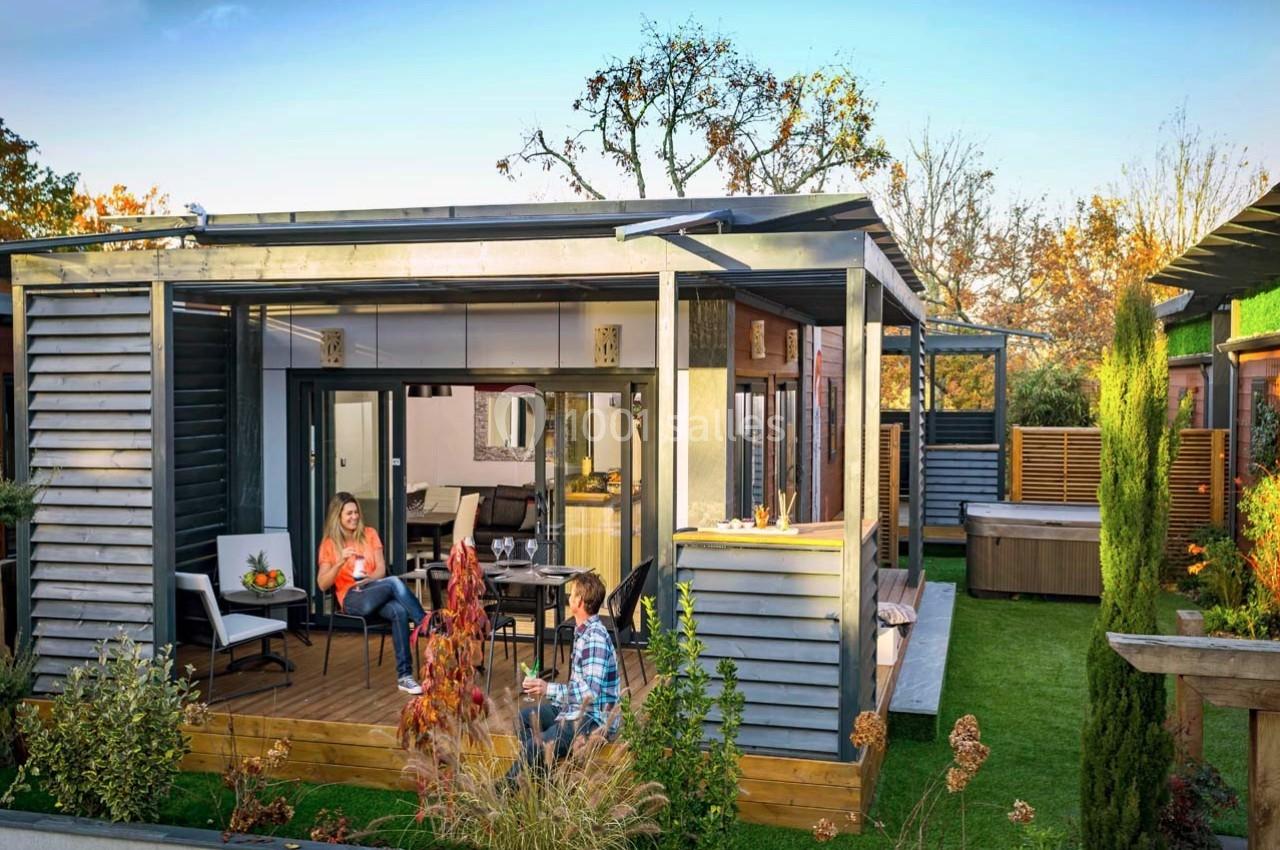 Terrasse en bois avec deux personnes assises, entourée de verdure et attenante à une maison moderne en bardage bois.