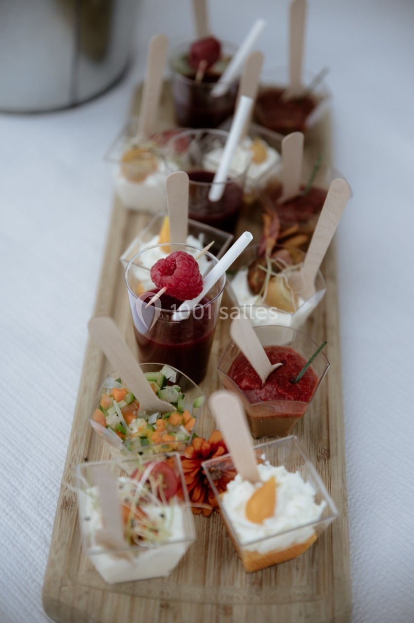 Assortiment de verrines et amuse-bouches variés présentés sur un plateau en bois.