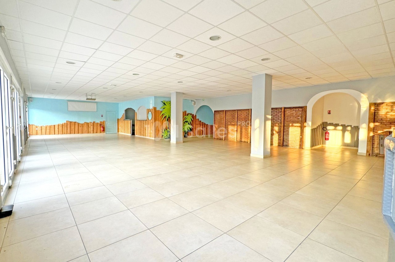 Salle spacieuse et lumineuse avec carrelage clair, murs décorés et grandes fenêtres laissant entrer la lumière naturelle.