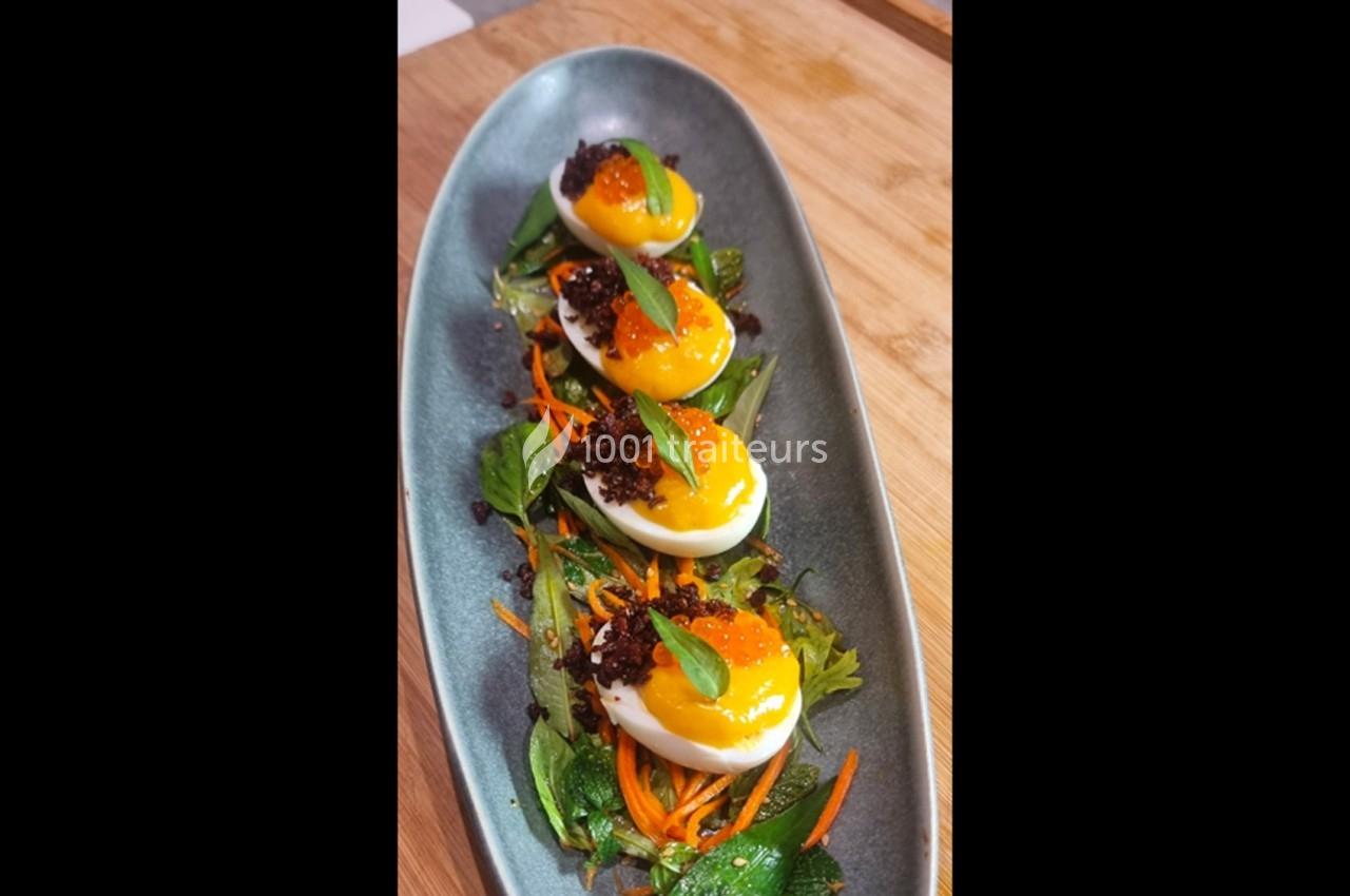 Œufs durs garnis de jaune coulant, œufs de poisson, miettes croustillantes et herbes sur un lit de légumes frais.