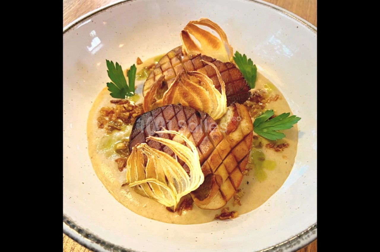 Assiette de purée crémeuse garnie de légumes grillés, chips croustillantes et feuilles de persil frais.