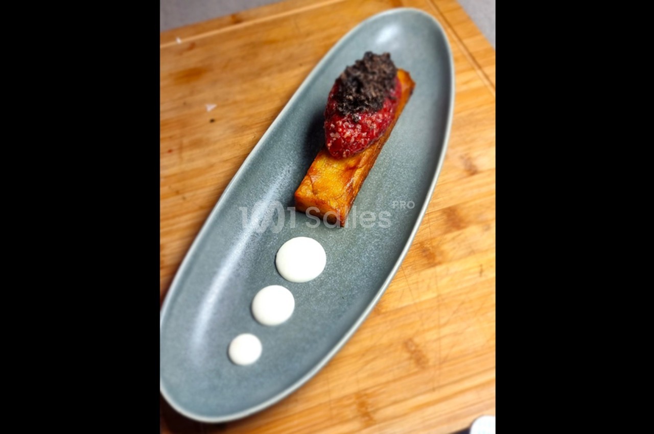 Assiette ovale contenant une présentation soignée de polenta, purée rouge, tapenade et trois points de sauce blanche.