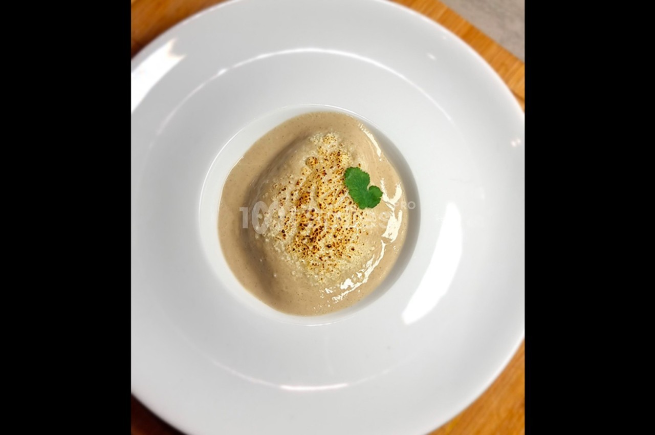 Purée crémeuse servie dans une assiette blanche, garnie d'une feuille de coriandre et légèrement grillée.