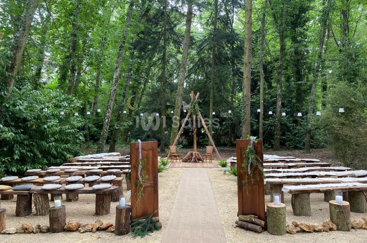 Allée centrale menant à un espace de cérémonie en plein air, entouré de bancs en bois et décoré de végétation.