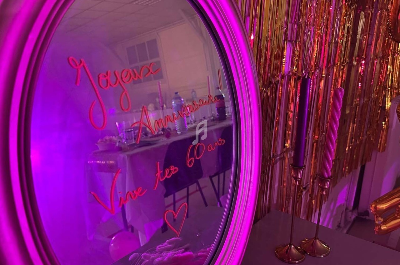 Texte alt : Miroir décoré avec l'inscription ’Joyeux Anniversaire, Vive tes 60 ans’ reflétant une table de fête et des…