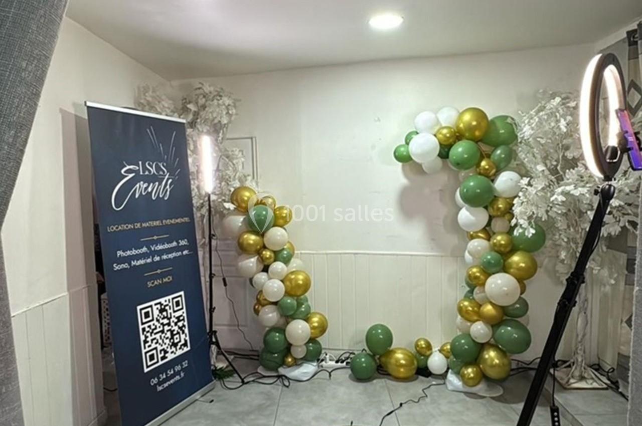 Anneau lumineux, plateforme 360° et décor de ballons verts, blancs et dorés dans une pièce aménagée pour un événement.